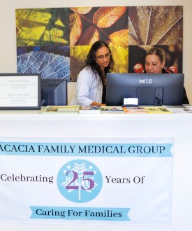 A photo of a doctor speaking to a colleague at the front desk of a doctor's office.