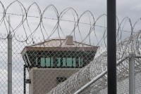 A photo of a barbed wire fence seen in front of a guard tower.