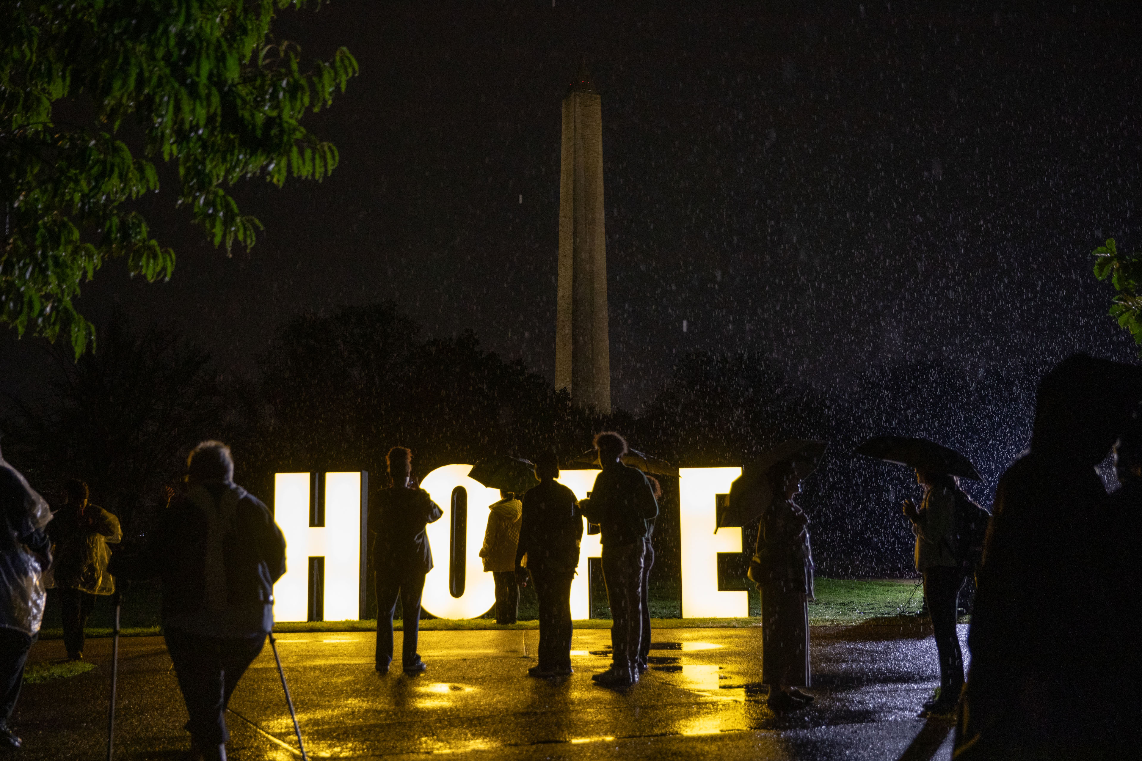 A photo of a memorial in downtown Washington D.C. Large letters that spell "HOPE" are illuminated as people walk around them.