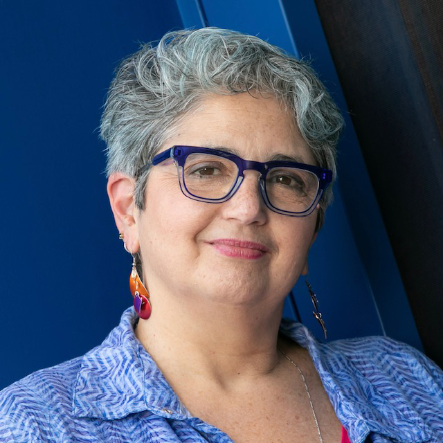 A portrait of a woman with short grey hair and glasses.