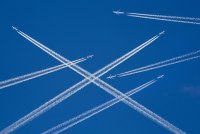 A photo illustration of a sky filled with airplanes releasing contrails behind them.