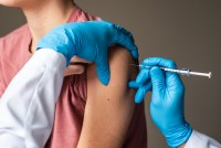 A photo of a medical worker using a syringe to give a child a vaccine.