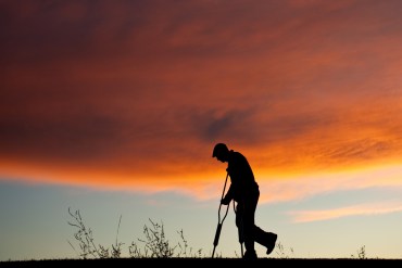 A silhouette of an injured senior man with crutches.