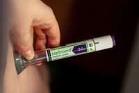 A photo of someone using a Zepbound injector pen on their stomach.