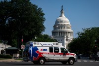 A photo of an ambulance driving by in Washington, D.C. The rotunda of the U.S. Capitol is prominent in the background.