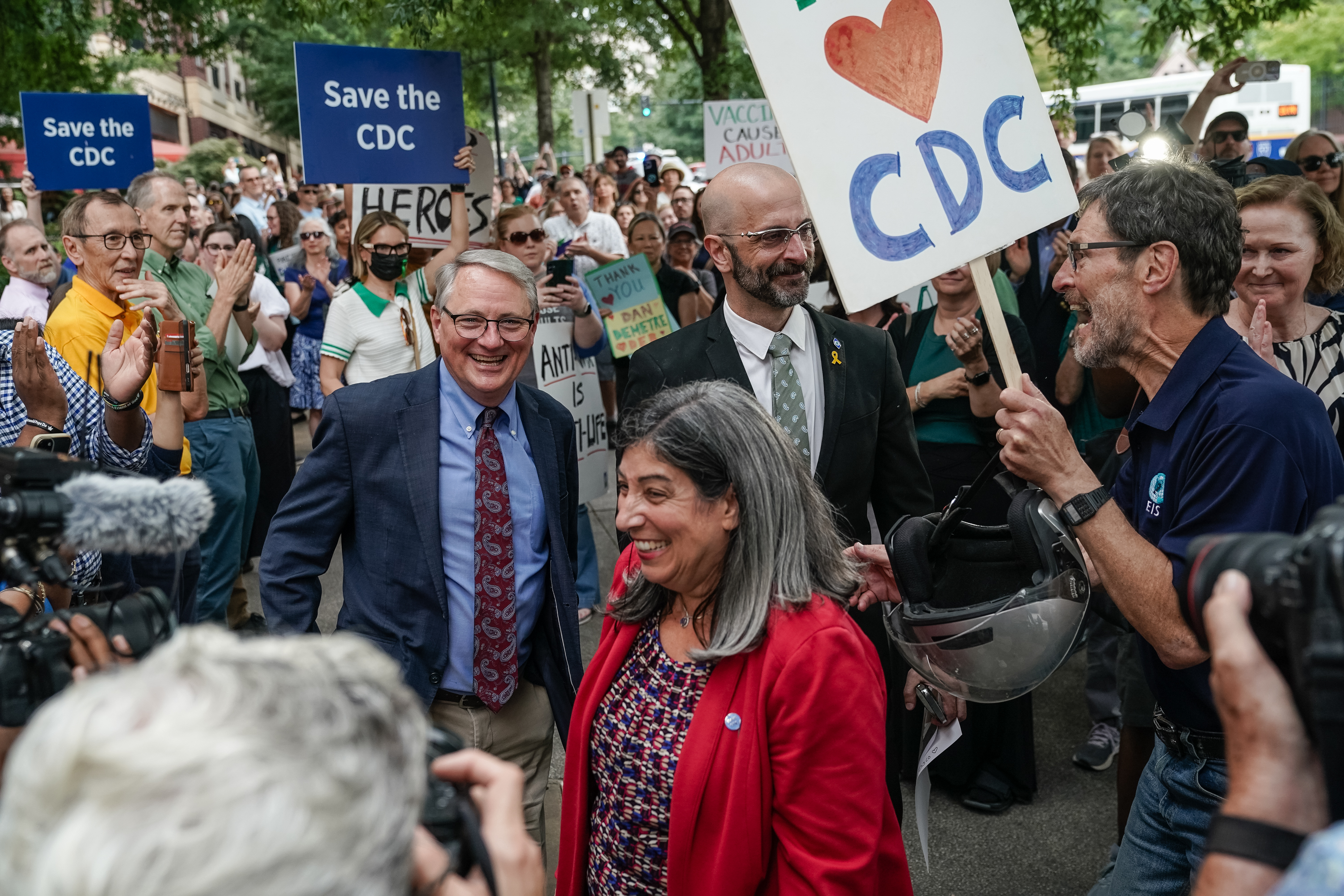 Former CDC officials Dan Jernigan Deb Houry, and Demetre Daskalakis smile at CDC employees holding signs of support.
