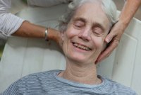 A photo of an elderly woman receiving a head massage.