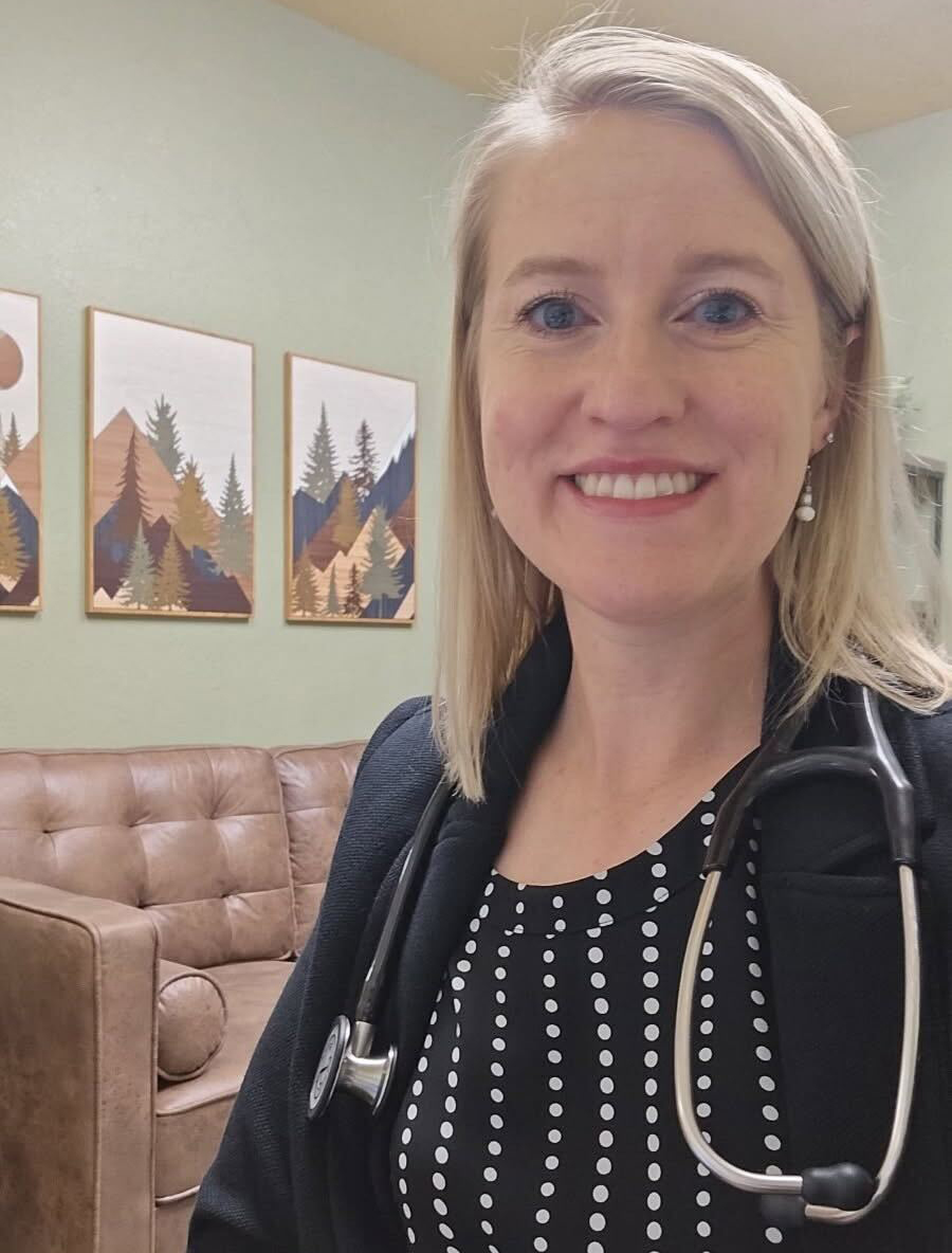 A photo of a woman taking a selfie indoors. A stethoscope is around her neck.