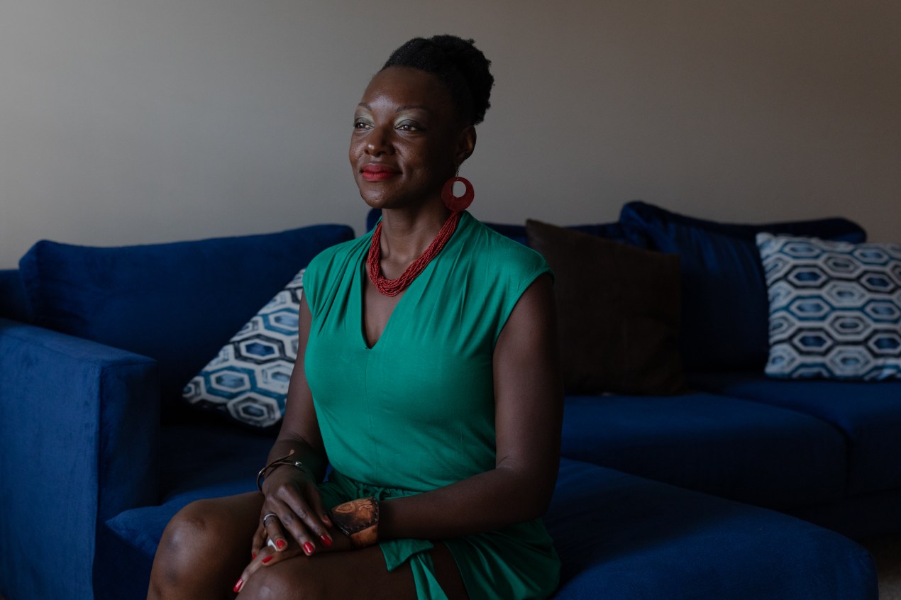 A woman in a green dress sits on a couch.