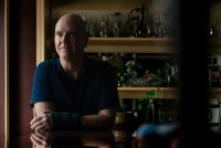A photo of Tim Winard sitting at a table beside a window. His face and much of his surroundings are cast in shadow.